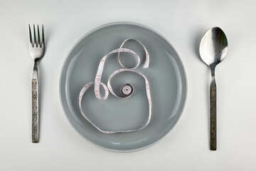 plate fork spoon and measuring tape on a white background concept diet nutrition