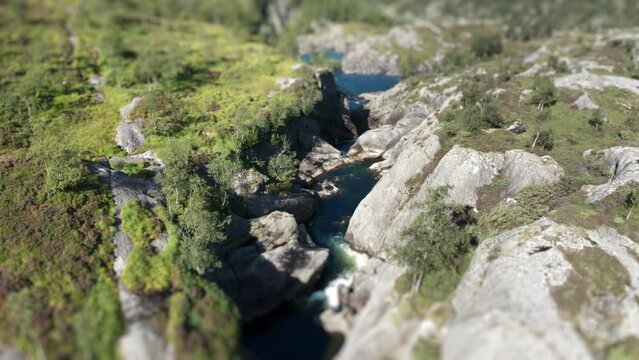 An aerial view of the river flowing through the valley. Tilt-shift video, slow-motion.