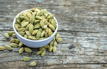Closeup of Dry Cardamom or Cardamon in  a White Bowl on  Wooden Background with Copy Space in Horizontal Orientation
