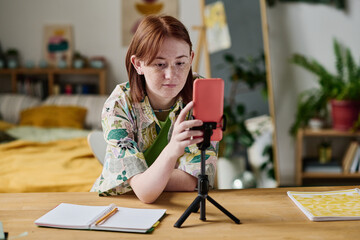 Teenage girl turning on the record on her smartphone to shoot the video content for her blog