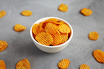 Crispy Barbeque Potato Chips in a Bowl on a gray background, side view.