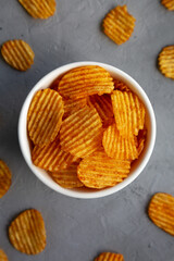 Crispy Barbeque Potato Chips in a Bowl on a gray background, top view. Flat lay, overhead, from above.
