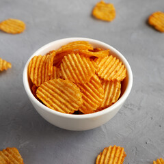Crispy Barbeque Potato Chips in a Bowl on a gray background, side view.
