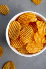 Crispy Barbeque Potato Chips in a Bowl on a gray surface, top view. Flat lay, overhead, from above.