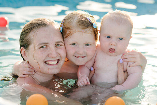 Mother and kids having fun in the swimming pool. Summer leisure and family holidays and vacation concept. People swim in a metal frame pool in the backyard. Mom with children: baby son and daughter.