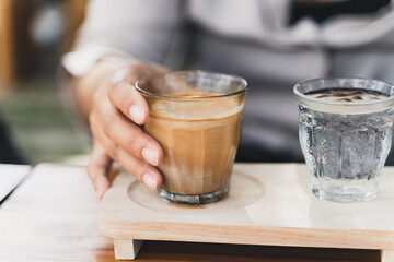 Woman is holding a glass of espresso shot over cold fresh milk. Dirty Coffee, Coffee menu, Milk Coffee