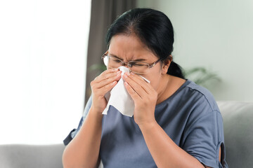 Cold sick woman got nose allergy cough or sneeze with tissue paper sitting on the sofa. Healthcare and medical concept..