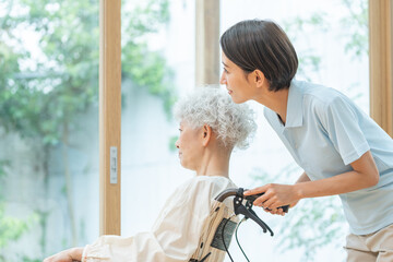 車椅子に乗ったシニア女性と介護士（介護・福祉・ヘルパー）