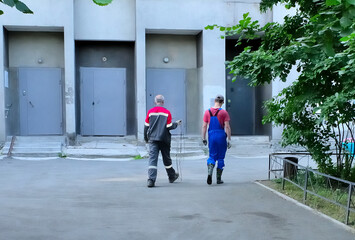 Municipal workers walk along the sidewalk on a summer day