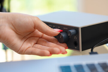 Unrecognizable young woman hands adjusting audio mixer setting sound in home studio close up