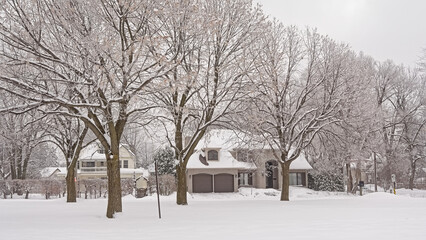 Suburbian houses in the snow along a park with bare trees in Montreal, Quebec, Canada 