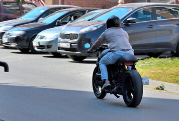 Fototapeta premium A man rides a motorcycle down the street on a summer day