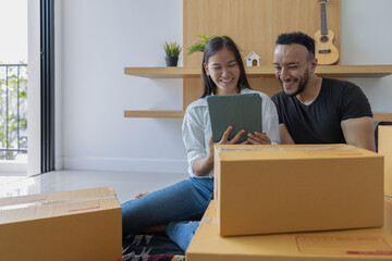 The concept of moving house. Couple holding a tablet checking a cardboard box Packing stuff to move...
