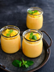 Mango pudding topped with mango chunks and mint leaf garnish. Served in a jar, fresh and healthy

