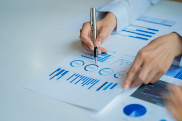 Businessman holding pen and paper pointing chart summary analysis calculating annual business report using laptop at desk in office concept accounting