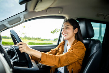 Fototapeta na wymiar Young beautiful asian women getting new car. she very happy and excited. Smiling female driving vehicle on the road on a bright day.