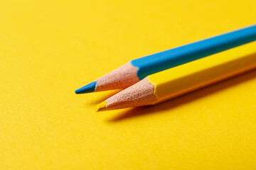 Pencils in colors of Ukrainian flag on yellow background