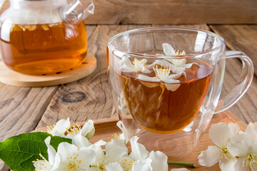 Front view of natural fragrant jasmine tea in a glass transparent cup with double bottom. white flowers of the plant. natural drink.