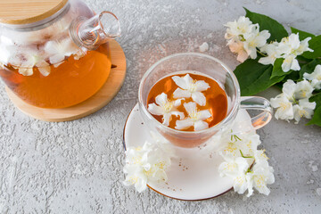 tea ceremony with jasmine tea. exquisite delicious aroma of tea. a glass cup filled with tea and jasmine flowers. gray background.