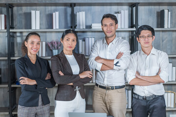 Portrait Group of Asian young business people stand together in office. Attractive businessman and woman standing crossing arm with confident and feel successful, smile and look at camera at corporate