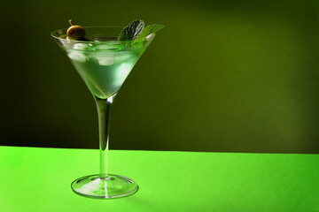 Martini with olives and ice on a green background