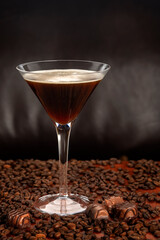 Coffee liqueur in a martini glass against a dark background with coffee beans and dark chocolate