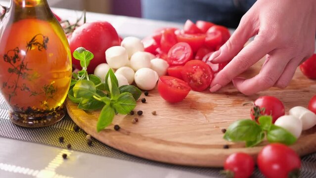 making caprese salad slicing cherry tomatoes on wooden cutting board