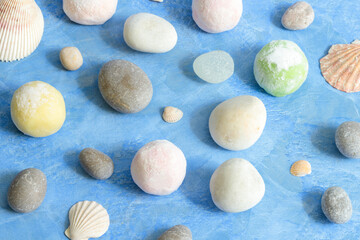 Fototapeta na wymiar Japanese dessert mochi on a blue background with white sea pebbles and shells. Close-up, concept, design idea