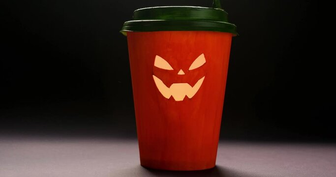 Orange coffee paper cup in the form of Halloween pumpkins on a dark background. 4K stop motion animation