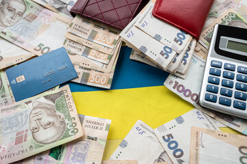 Ukraine national flag with UAH paper money in wallet, credit card calculator,