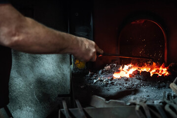 Close up view of heated metal and fire oven. Blacksmith in the production process of other metal...