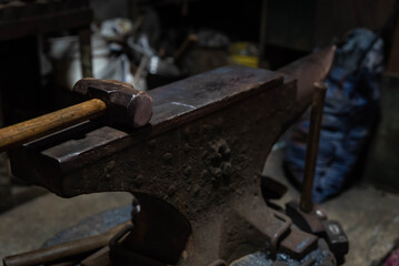 Close up view of heated metal and anvil. Blacksmith in the production process of other metal products handmade in the forge. Metalworker forging metal with a hammer into knife. Metal craft industry.