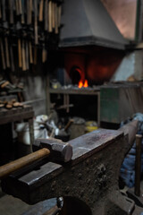 Close up view of heated metal and anvil. Blacksmith in the production process of other metal products handmade in the forge. Metalworker forging metal with a hammer into knife. Metal craft industry.