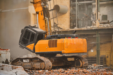 Hydraulic excavator with caterpillars demolishes old factory