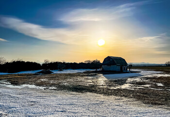 Fototapeta na wymiar A snowmelting farm shining in the sunset