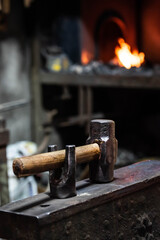 Close up view of heated metal and anvil. Blacksmith in the production process of other metal products handmade in the forge. Metalworker forging metal with a hammer into knife. Metal craft industry.