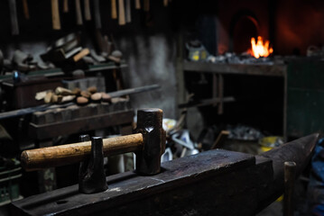 Close up view of heated metal and anvil. Blacksmith in the production process of other metal products handmade in the forge. Metalworker forging metal with a hammer into knife. Metal craft industry.