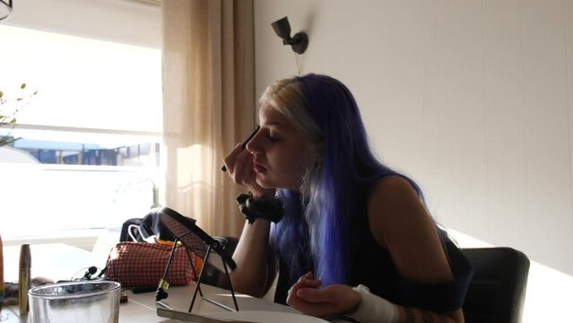 Street Party Girl Applying Makeup In The Room In Daylight. medium shot
