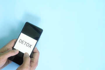 Digital detox concept. Hand holding a mobile phone in blue background flat lay.