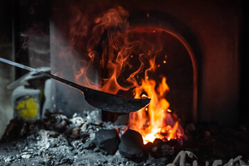 Close up view of heated metal and fire oven. Blacksmith in the production process of other metal products handmade in the forge. Metalworker forging metal into knife. Metal craft industry.