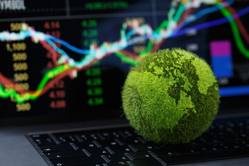 Green Globe on laptop keyboard with Stock graph on the laptop screen. Green business concept....