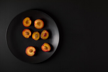 Plums on the black plate and black background.