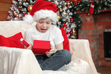 Fototapeta na wymiar Merry Christmas kids. Emotions of a child. Joyful surprised kid boy in Santa's hat opened a Christmas box with a gift from Santa Claus near the Christmas tree with Christmas tree lights