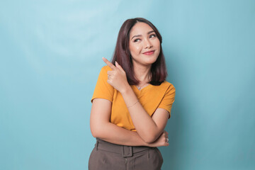 An excited young woman presenting and pointing upwards the copy space, isolated on blue background