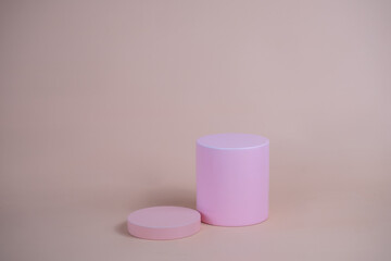 Empty podium for display cosmetic product. Platform arrangement in pink pastel color in trendy minimalist style. Composition of cylinders and cubes layout for feminine background