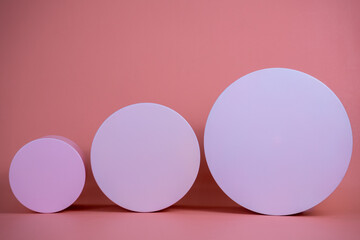 Empty podium for display cosmetic product. Platform arrangement in pink pastel color in trendy minimalist style. Composition of cylinders and cubes layout for feminine background