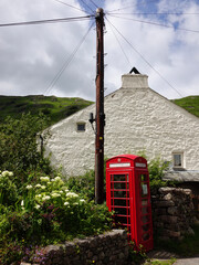 red telephone box with phone wires and old cottage in lake district of england