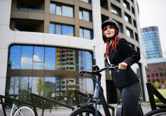Portrait of businesswoman commuter on the way to work with bike looking at camera, sustainable...