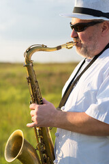 Man playing jazz on saxophone in the spring nature on a sunny day