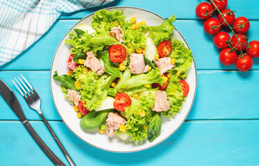 Tuna Fish Salad with Lettuce, Cherry Tomatoes, Cucumber and Corn on blue wooden background